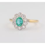 A yellow metal oval emerald and diamond cluster ring, the centre stone 0.6ct, the 10 brilliant cut