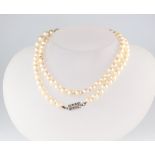 A strand of 84 cultured pearls, each approx. 5mm, with a white metal set 8 stone diamond clasp, 65cm