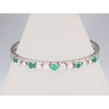 A white metal stamped 750 diamond and emerald bracelet comprising 8 brilliant cut diamonds approx.