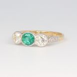 A yellow metal stamped 18ct emerald and diamond ring, the oval centre stone 0.7ct, the 2 brilliant