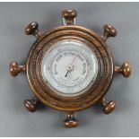 A 1930's aneroid barometer with silvered dial contained in an oak ships wheel style case 24cm
