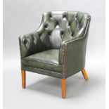 A Georgian style tub back club armchair upholstered in green buttoned leather, raised on square