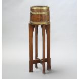 An Art Nouveau coopered oak and brass jardiniere stand raised on shaped supports with X framed