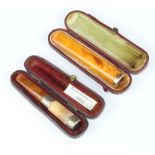 A yellow metal mounted amber cigar holder, cased, a silver mounted ditto Birmingham 1899