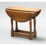 An oak utility oval drop flap tea table raised on turned and block supports 50cm h x 60cm w x 21cm