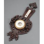 A French Edwardian aneroid barometer and thermometer with silvered dial, contained in a carved and