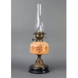 A Victorian oil lamp with orange, opaque and floral patterned reservoir, raised on a gilt and