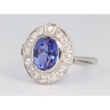 A white metal stamped plat. Art Deco style oval tanzanite and diamond cluster ring, the centre stone