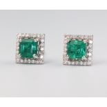 A pair of white metal stamped 18ct princess cut emerald and diamond ear studs, the centre stones 1.