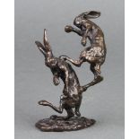 In the manner of Richard Cooper & Co., an unmarked figure group of 2 boxing hares, raised on an oval