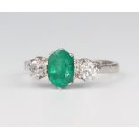 A white metal stamped Plat. oval emerald and diamond ring, the centre oval emerald 1.1ct, the 2