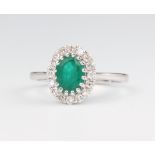 A white metal stamped 18ct oval emerald and diamond cluster ring, the centre stone 1.31ct, brilliant