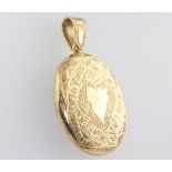 A yellow metal 18ct oval engraved locket with vacant cartouche, gross weight 19.4 grams The loop