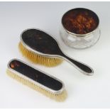 A silver and tortoiseshell dressing table set comprising powder jar, hair brush, clothes brush,