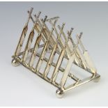 A silver plated novelty 7 bar toast rack in the form of crossed cricket bats on ball feet