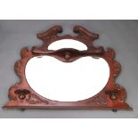 An Edwardian shaped plate over mantel mirror, fitted shelves, contained in a shaped mahogany frame