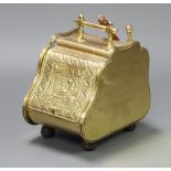 A Victorian Continental embossed brass coal bin raised on turned feet with fall front decorated a