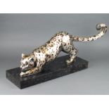 A resin figure of a crouching cheetah raised on a marble base 27cm x 55cm x 19cm