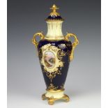 Coalport, a blue and gilt twin handled urn and cover with landscape panel decoration, the base
