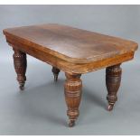 A Victorian rectangular oak dining table raised on turned and reeded supports with brass caps and