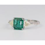 A white metal stamped 18ct emerald and diamond ring, the centre emerald approx. 1.65ct, the