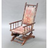 A 19th Century American turned mahogany rocking chair, the seat and back upholstered, raised on