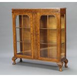 A Queen Anne style figured walnut display cabinet with adjustable shelves enclosed by arched