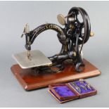 A Wilcox and Gibbs manual sewing machine together with various attachments contained in a leather