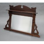 An Art Nouveau rectangular bevelled plate over mantel mirror contained in a shaped and pierced