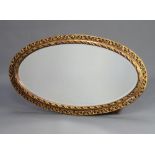An oval bevelled plate wall mirror contained in a decorative pierced gilt frame 102cm h x 59cm w