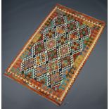 An orange, green, black and white ground Chobi Kilim rug with all over geometric design 203cm x