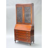 An Edwardian inlaid mahogany bureau bookcase, the upper section fitted shelves enclosed by