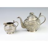 An Indian white metal baluster teapot decorated with figures having an elephant finial, 688gms