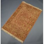 A pink and gold ground machine made Persian style rug 182cm x 122cm There is wear to the binding