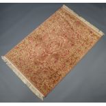A pink and gold ground machine made Persian style rug with central medallion 180cm x 120cm