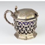 A Victorian pierced silver octagonal mustard with scroll decoration and blue glass liner, London