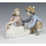 A Lladro figure of a seated boy and girl 5454 15cm together with a Nao figure of a girl holding a