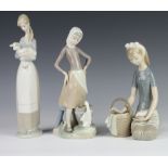 A Lladro figure of a girl holding a lamb 26cm, a ditto of a goose girl with pail 23cm and a kneeling
