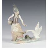 A Lladro figure of a girl holding a basket of eggs with a goose at her feet 19cm