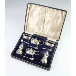 A silver 6 piece condiment set with beaded decoration and pad feet, with blue glass liners,
