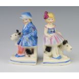 A pair of Goebels style Art Deco bookends in the form of a boy and girl with dogs no.3590 14cm