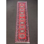 An Afghan red, green and brown ground runner with 10 medallions to the centre 336cm x 81cm