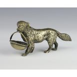A silver plated figure of a standing dog holding a basket in its mouth 14.5cm