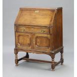 A 1930's oak Jacobean style bureau, the fall front revealing a well fitted interior above 1 long