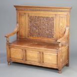 A Victorian carved light oak settle with moulded and dentil cornice, panelled back, the seat with