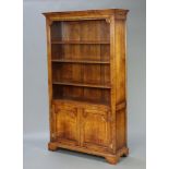 An Ipswich style carved oak bookcase with moulded cornice and adjustable shelves, the base fitted