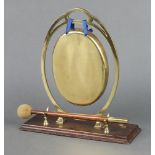 An Art Nouveau oval brass tea gong raised on a rectangular oak base, complete with beater, 28cm x