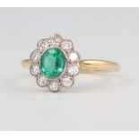 A yellow metal oval emerald and diamond cluster ring, the centre stone 0.65ct, the 10 brilliant