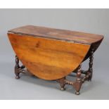 An 18th Century oak gateleg drop flap dining table raised on turned supports with turned stretcher