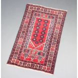 A red and brown ground Baluchi rug with 12 octagons to the centre 132cm x 82cm